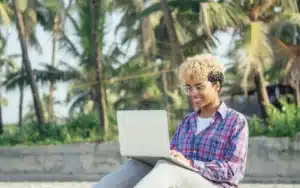 Entrepreneur aux Antilles Guyane travaillant sur un ordinateur dans un cadre tropical, symbolisant le marketing digital local.